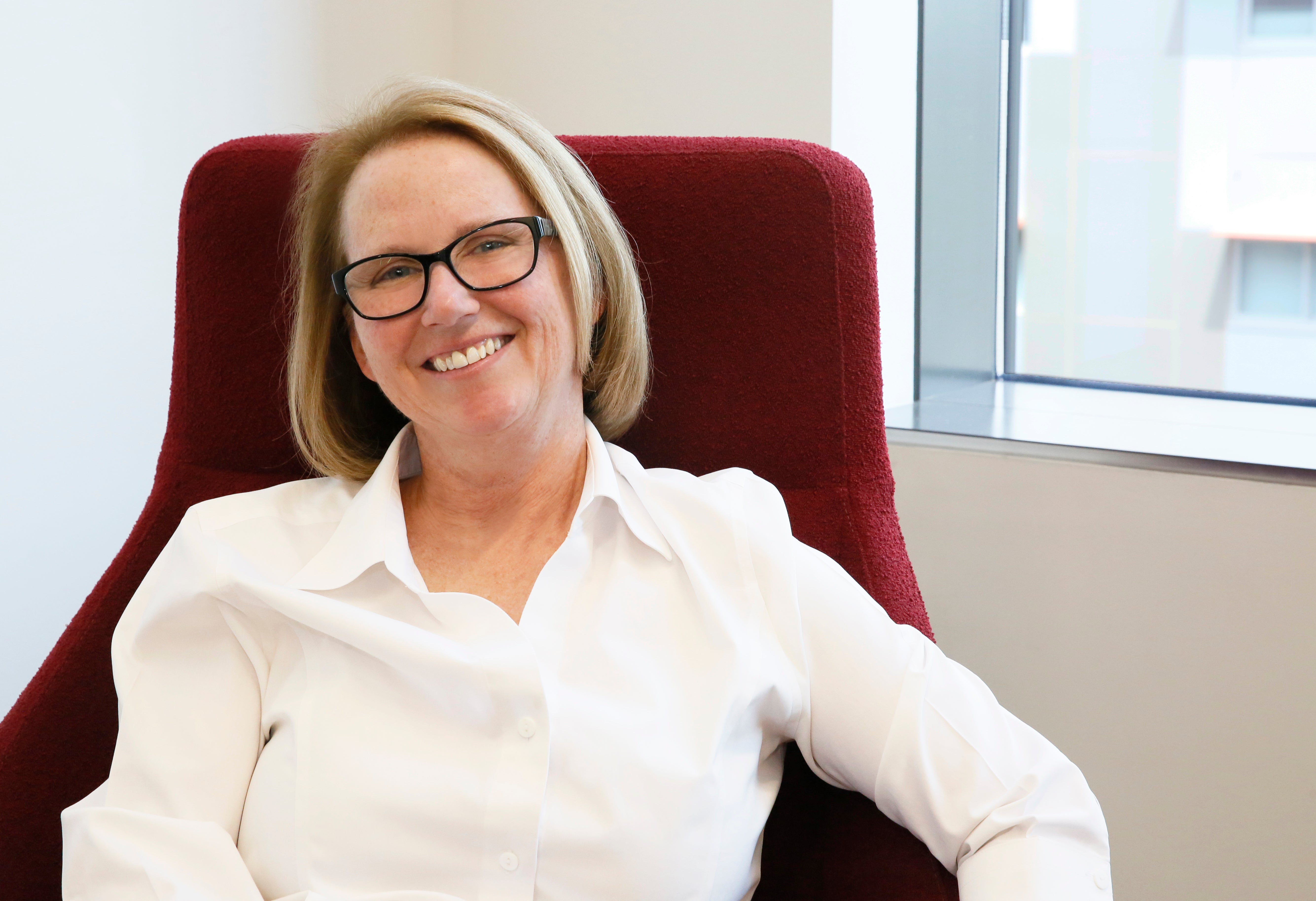 Judy Stinson sitting in a maroon ASU Law chair smiling.