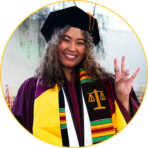 A student smiles, making the forks up hand sign, at the Spring 2025 JD/LLM convocation ceremony