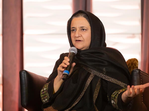 A woman in black clothing speaks into the microphone.