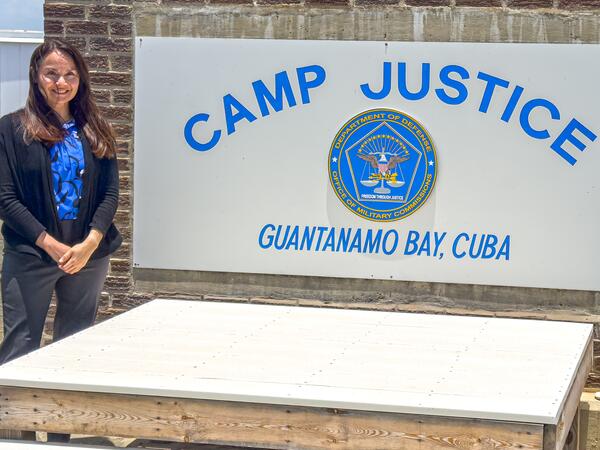 A brunette woman poses in front of a sign.