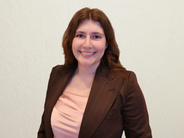 A brunette woman in a black blazer smiles for the camera.